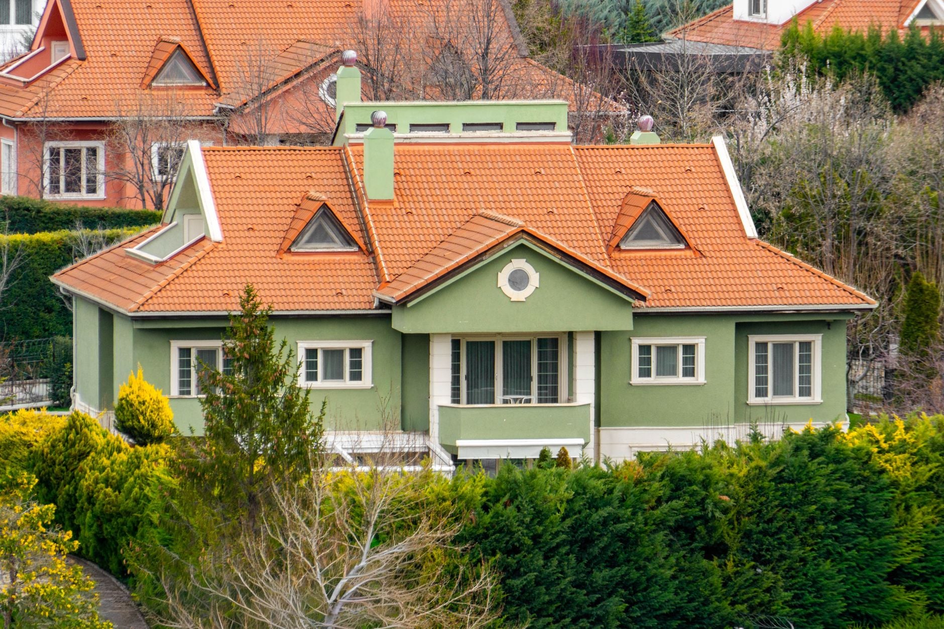 A picturesque green house with an orange roof surrounded by greenery in Ankara, Türkiye.